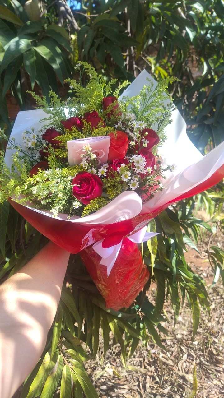 buquê de rosas vermelhas e laranjas com flores brancas e folhagens, embalado em papel branco e vermelho com la
