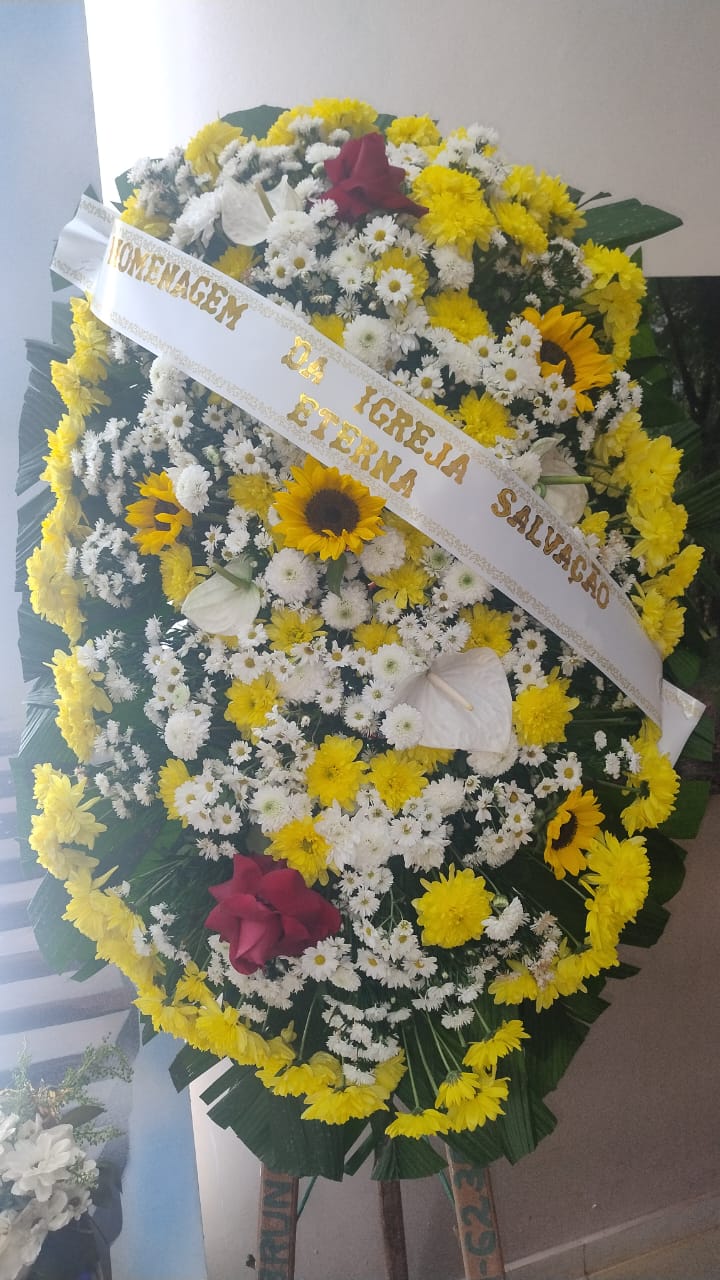 coroa de flores fúnebre com margaridas brancas, crisântemos amarelos, girassóis e rosas vermelhas, com faixa b